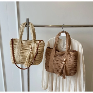 Close-up of woven straw tote bags with wooden bead tassels and leather straps
