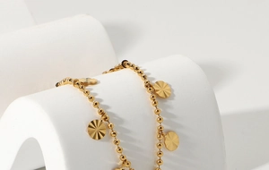 Macro view of 18K gold plated beaded chain anklet with sunburst petal charms