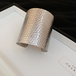 Macro view of textured hammered silver bangle with irregular metallic honeycomb finish
