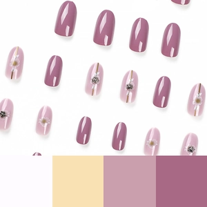 Pink and mauve press-on nails with white floral patterns and golden accents on white background