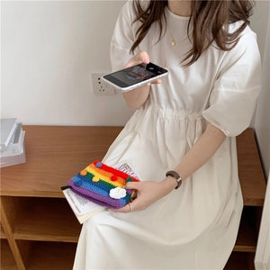 Detailed close-up of rainbow striped knit bag and white drawstring dress textures