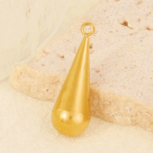 Macro detail of a golden teardrop pendant accessory with smooth polished metal finish