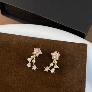 Macro shot of pink star-shaped gemstone earrings with pearls on a brown display mat