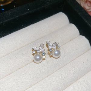 Detail of silver needle butterfly pearl earrings with sparkling zircons in a jewelry box