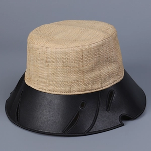 Dettaglio della trama in rafia e tesa in pelle nera con fori a goccia sul cappello a secchiello