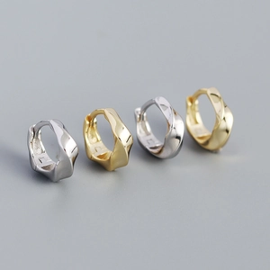 Macro shot of minimalist twisted texture metal hoop earrings in gold and silver finish
