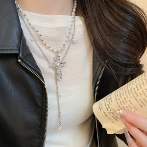 Détail du collier double couche avec pendentif croix et pompon en perle sur cuir noir