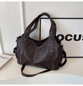 Detail of dark brown tote bag with multi-zipper pockets and soft leather texture