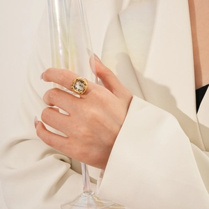 Dettaglio anello vintage in oro con zircone quadrato indossato da modella con bicchiere