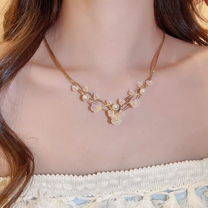 Three-layer gold necklace featuring white pearls and iridescent resin flower pendants