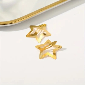Pair of minimalist 3cm gold star-shaped metal hair clips on white background