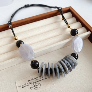 Close-up of leather cord necklace with marble-pattern beads on a velvet jewelry tray
