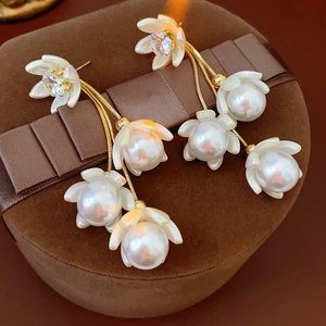 Detailed view of gold lily of the valley earrings with pearls on brown velvet box