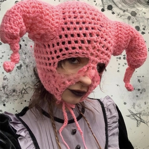 Detailed macro view of pink hand-knitted crochet clown balaclava with unique curled horns