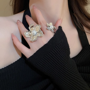 Detail of irregular pleated flower ring with pearl core and hammered metal texture