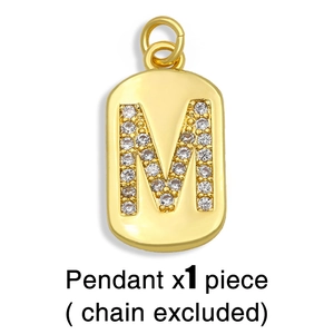 Detail showing gold-plated letter M pendant with paved rhinestones on white background