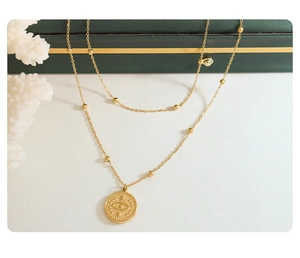 Detail of 18k gold layered necklace with eye pendant on a luxury green jewelry box
