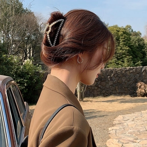 Elegant gold metal shark hair claw clip with pearls on a model in natural light