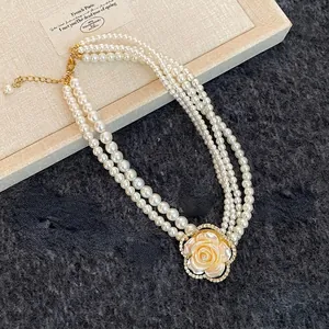 Close-up of multi-layer pearl necklace with a diamond-encrusted camellia flower pendant