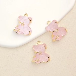 Detailed macro view of three pink translucent resin bear pendants with gold plating and zircons