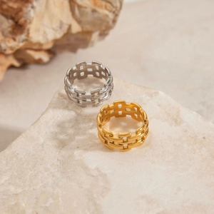 Draufsicht auf geflochtene Edelstahlringe in Gold und Silber auf einem Steinsockel