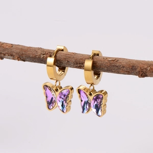 Gold hoop earrings with purple crystal butterfly pendants hanging on a branch