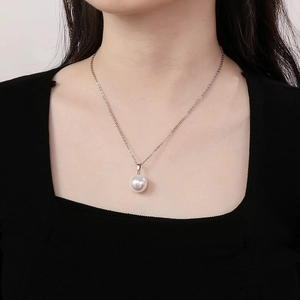 Detail of a minimalist pearl pendant on a silver steel chain worn on a model's neck