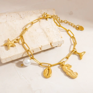 Detail of 18k gold starfish and pearl charms on stainless steel bracelet with shells