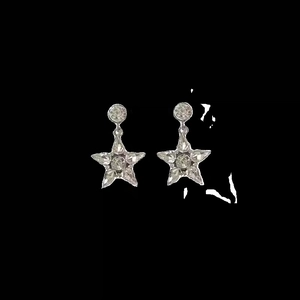 Gros plan de boucles d'oreilles étoiles argentées avec cristaux sur fond noir