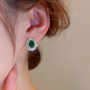 Close-up of elegant silver stud earring featuring an oval green emerald-cut zircon stone