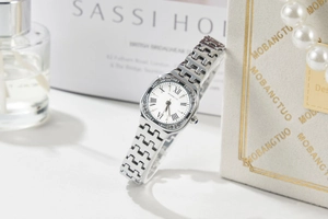 Detailed close-up of a silver square quartz watch with crystal bezel and Roman numerals