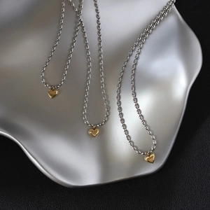 Elegant gold heart pendant on silver bead chain necklace displayed on metal tray