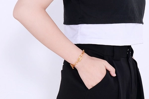 Detailed side view of a gold infinity link bracelet with a toggle clasp on a wrist