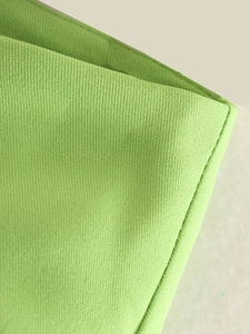 Detailed close-up of the vibrant green woven fabric texture and fine stitching on the skirt