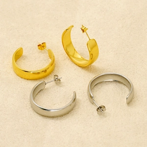 Macro view of minimalist gold and silver polished C-shaped thick hoop earrings