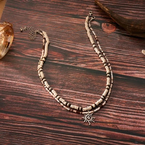 Detail view of double-layer beaded necklace set with sun pendant on a wooden background