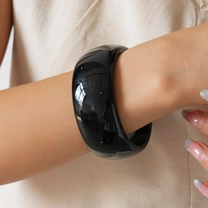 Close-up of minimalist thick black acrylic bangle with a high-gloss mirror finish on wrist