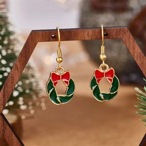 Detailed view of Christmas wreath earrings with red bow and green enamel on wood stand