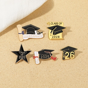 Detail view of 2026 graduation enamel pins featuring a black cap and golden scroll