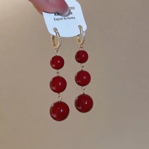 Elegant gold-plated hoop earrings with three red resin beads and shimmering rhinestones