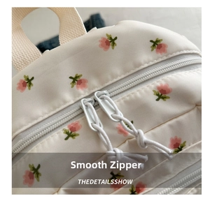 Macro shot of smooth dual-direction zippers on floral print backpack with knot pulls