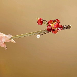 Detail view of a vintage gold hair pin with red plum blossoms and white pearl tassels