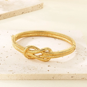 Macro detail of golden knot bracelet showing intricate spiral metal textures on stone