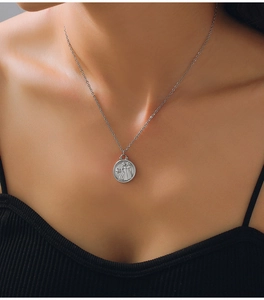 Macro detail of silver titanium steel necklace with Gemini zodiac and star pendant