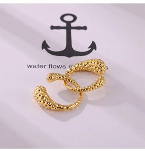 Macro shot of gold-plated hammered texture ear cuffs on a white logo presentation card