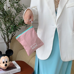 Detail of pink and green fabric makeup bag with metal zipper held by a model