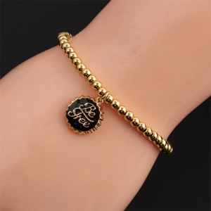 Goldenes Kugelarmband mit schwarzem Emaille-Anhänger und Be Free Gravur in Nahaufnahme