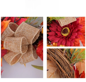 Close-up detail of artificial autumn wreath showing red flower and burlap bow texture