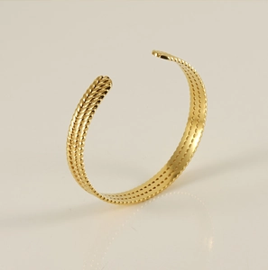 Detailed view of the gold-plated twisted texture on an adjustable open bangle bracelet