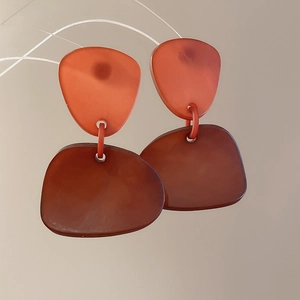 Detailed view of irregular acrylic geometric earrings with orange and brown resin texture